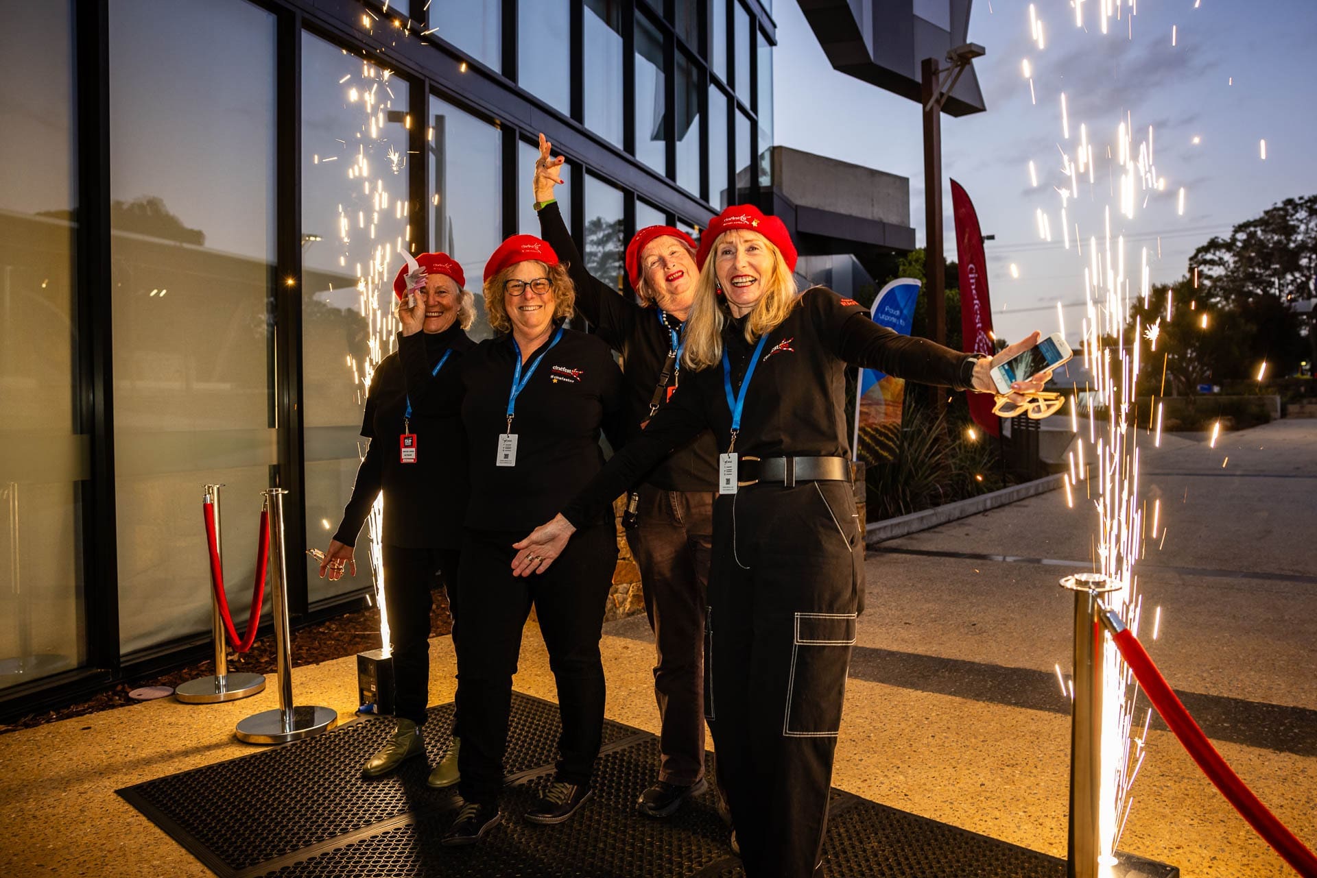 Four Volunteers Outside A Building Entrance, Posing With Their Arms In The Air Next To Cold Sparks.