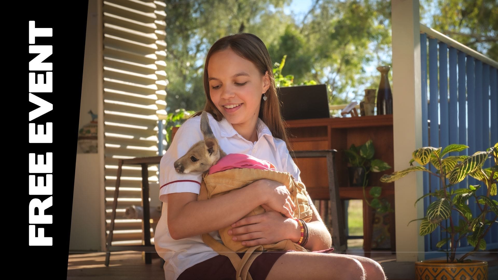 Young Girl Sitting Outside, Holding A Joey Wrapped In A Blanket.